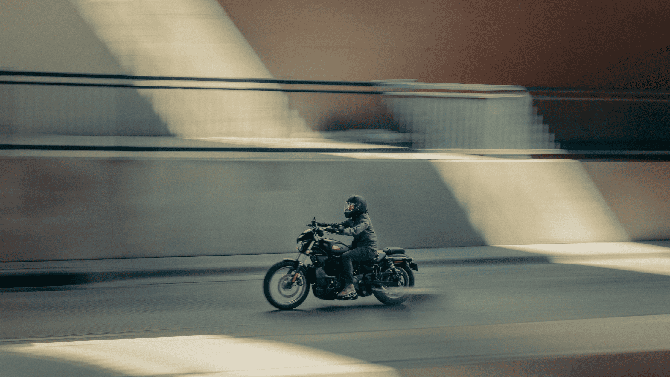 A lone motorcyclist rides a sleek sport motorcycle through an urban environment, captured with a mot…